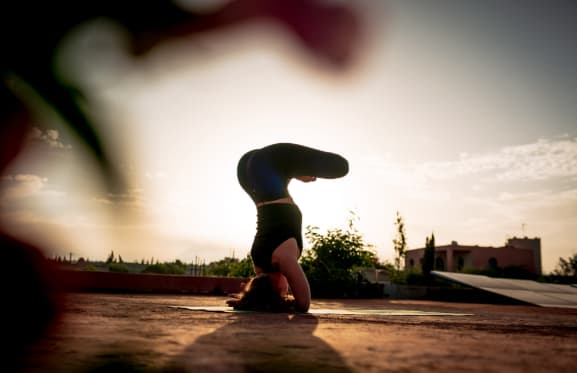 Pratiquante de yoga en appui sur la tête au coucher du soleil
