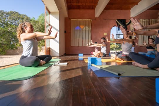 Formatrice de yoga guidant des élèves attentifs dans une pratique du matin