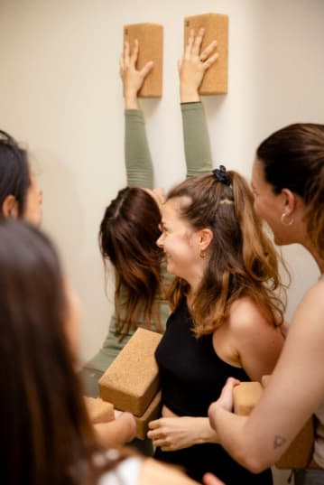Élèves d'une formation de yoga ĀYU qui pratiquent des exercices au mur dans la bonne humeur.