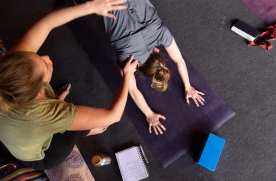 Formatrice aidant une élève à comprendre les activations subtiles dans la posture du chien tête en bas en formation de yoga