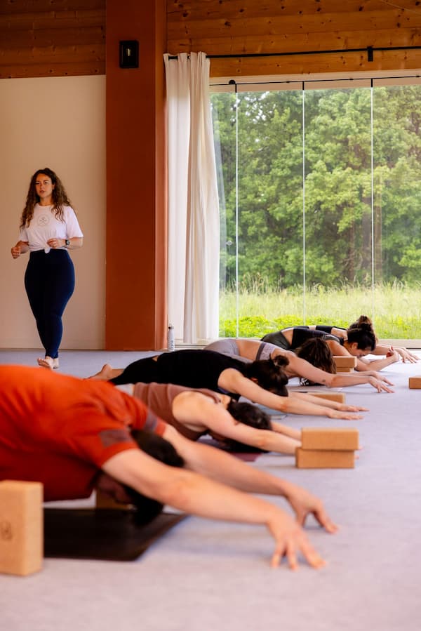 Formatrice guidant des élèves en posture de l'enfant d'une formation de yoga ĀYU